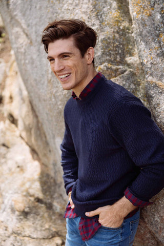 Man in a Southern Tide sweater leaning with hand in pockets.
