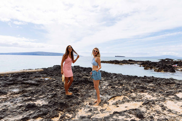 two girls walking on rocks on beach