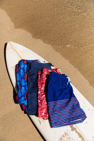 mens swim trunks on surfboard