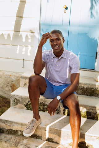 Man sitting on steps wearing heathered performance polo from Southern Tide