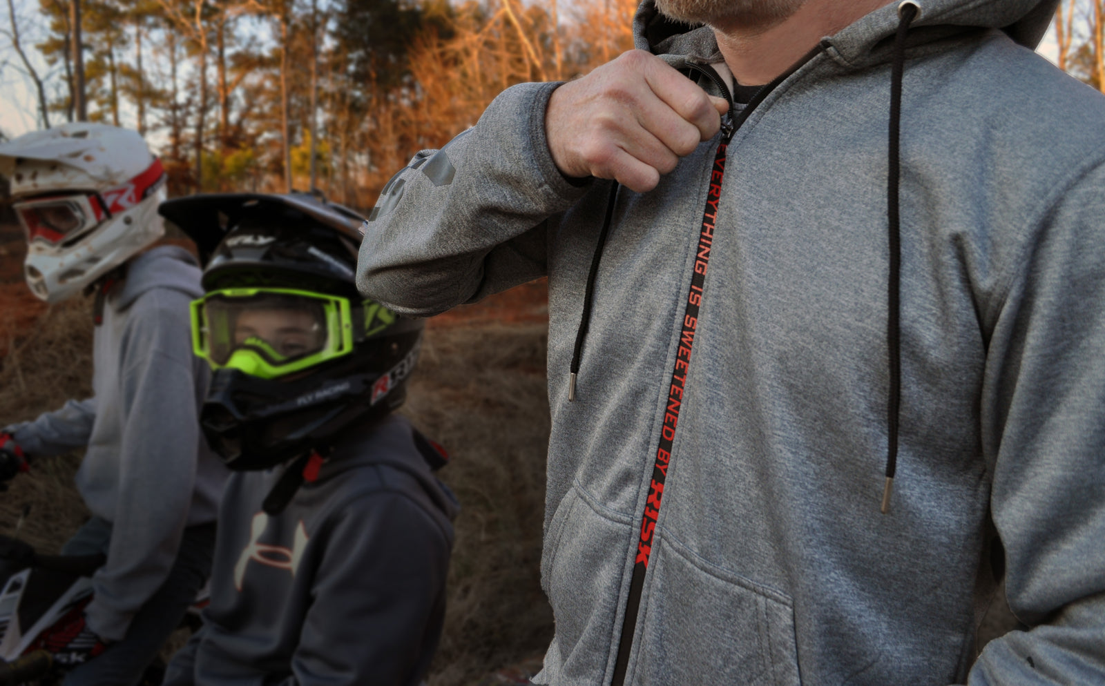 close up of a male wearing a Risk Racing zipper jacket pulling the zipper up revealing the hidden zipper message