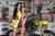 August's Risk Racing Moto Model Samantha Heady posing in various bikinis & Risk Racing Jerseys next to a dirt bike that's sitting on a Risk Racing ATS stand - Pose #17