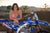 December's Risk Racing Moto Model Kelly Perez posing in various bikinis and Risk Racing Jerseys next to a dirt bike that's sitting on a Risk Racing ATS stand - Pose #7