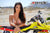 Risk Racing's March Moto Model Amber Juliana wearing a bikini standing behind a motocross bike resting her forearms on the seat - medium shot - white fenced off MX track in background