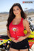 Risk Racing's March Moto Model Amber Juliana wearing a red Risky moto chick daisy tank top touching her navel area with both hands while standing in front of a motocross bike - close up shot - white fenced off MX track in background
