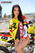 Risk Racing's March Moto Model Amber Juliana wearing a Yellow and Red VENTilate V2 Jersey and a smile in front of a motocross bike - close up shot - white fenced off MX track in background