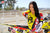 Risk Racing's March Moto Model Amber Juliana wearing a Yellow and Red VENTilate V2 Jersey in front of a motocross bike - close up shot - white fenced off MX track in background