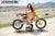 Risk Racing's March Moto Model Amber Juliana wearing a white bikini in front of a motocross bike that's sitting on an ATS MX Stand - wide shot - MX track in background