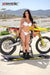 Risk Racing's March Moto Model Amber Juliana wearing a white bikini standing in front of a motocross bike hands out to the sides touching the bike - medium wide shot - white fenced off MX track in background