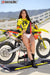 Risk Racing's March Moto Model Amber Juliana wearing a Yellow and Red VENTilate V2 Jersey and white bikini bottoms leaning back on a motocross bike that's sitting on an ATS stand - medium shot - white fenced off MX track in background