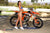 Risk Racing's May Moto Model Natalie Nicole wearing a 2 piece bikini posing sideways in front of a motocross bike that's sitting on an ATS Stand and Factory Pit mat by Risk Racing. She on her tip toes with left hand on the seat and right lightly touching her belly. - wide shot - white fenced off MX track in background