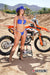 October's Risk Racing Moto Model Dani Hamilton posing in various bikinis and Risk Racing Jerseys next to a dirt bike that's sitting on a Risk Racing ATS stand - Pose #33