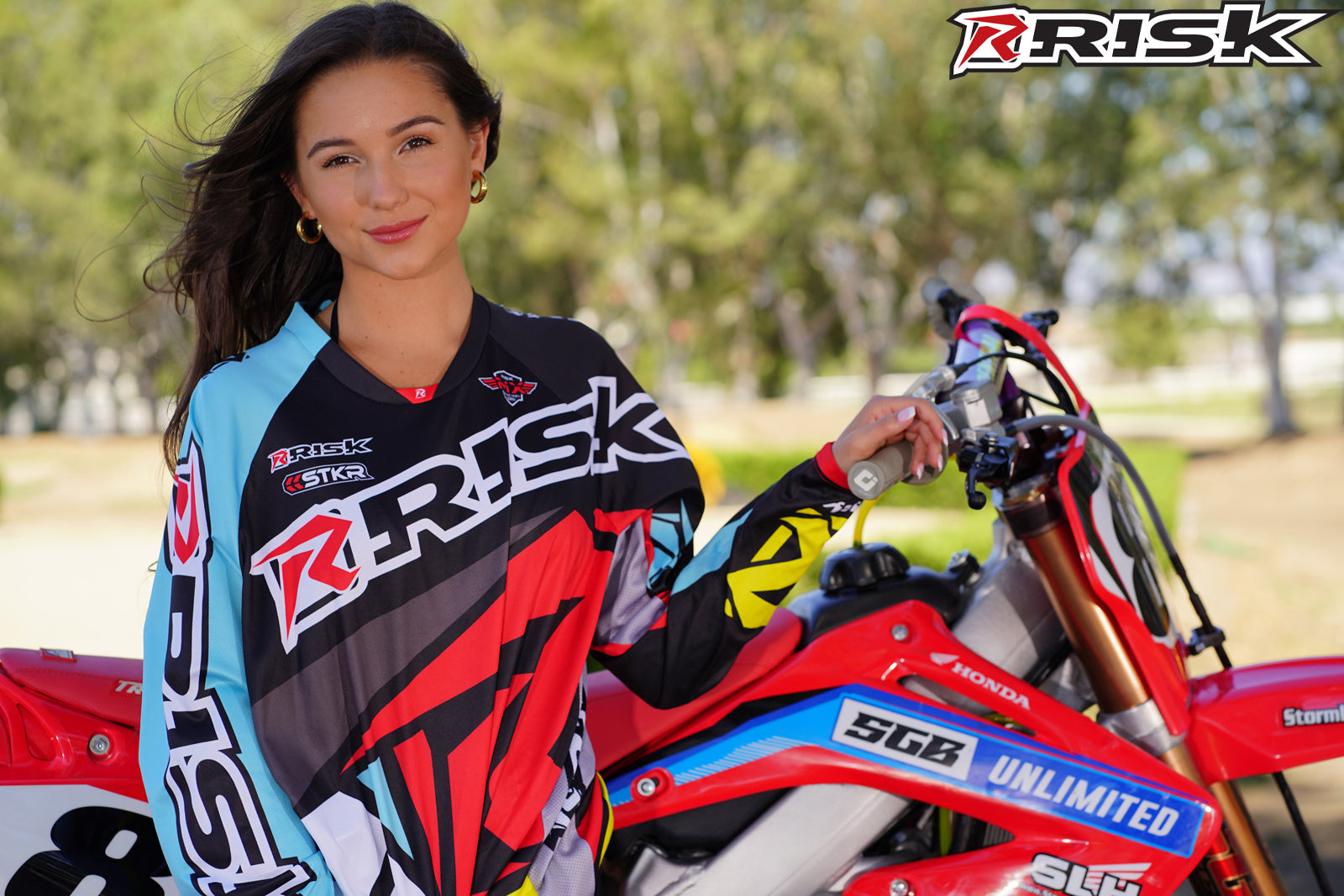 July's Risk Racing Moto Model Samantha Heady posing in various bikinis & Risk Racing Jerseys next to Alex Ray's Honda CR250R that's sidding on a Risk Racing ATS stand - Pose #3