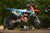 lifestyle img of a CLUBMX KTM with full graphics sitting on an ATS adjustable top stand by Risk Racing