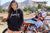 Close up of February Moto Model Alliyah wearing a Black Risk Racing Hoodie revealing a small amount of blue bikini below with her hands in hoodie pockets standing in front of a KTM dirt bike #277 at a MX track with mountains in background.
