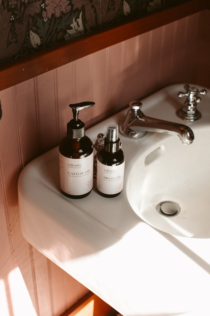 Amber bottle of organic castor oil and argan oil on bathroom sink