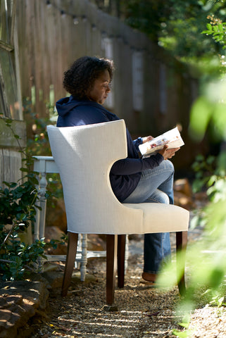 girl reading in a garden, sitting in Cudo's Cinnamon Dining Chair