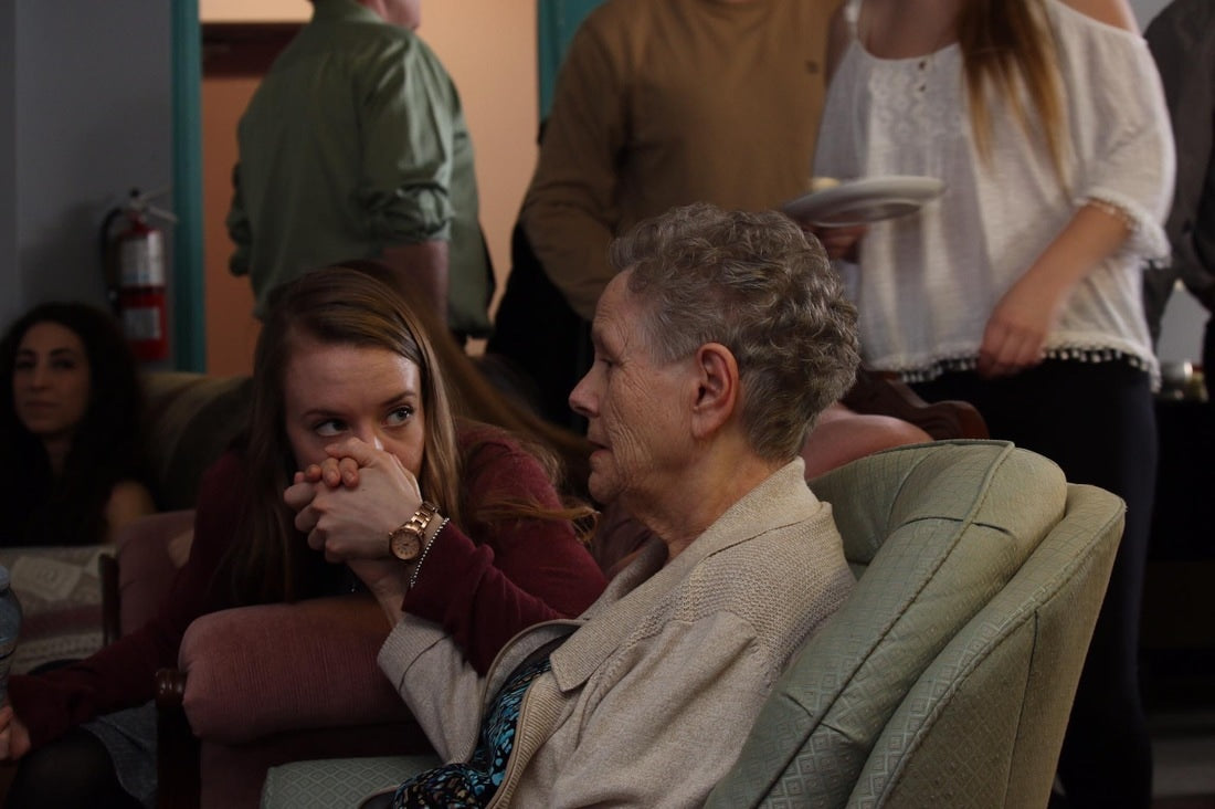 granddaughter kissing hand of grandma with dementia
