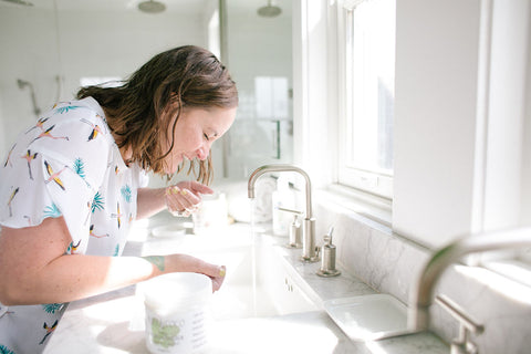 Woman washing face with Moisturizing Exfoliator