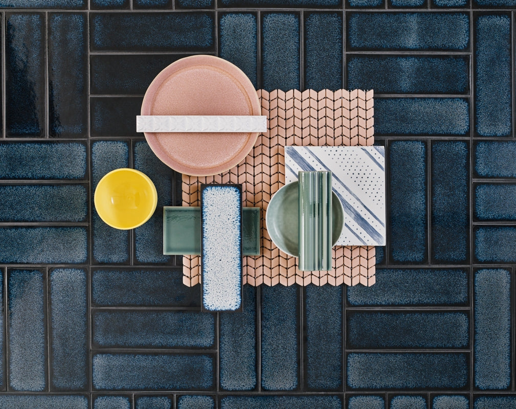A flatlay showcasing Claybrook tile designs set against a background of their Raku Yokohoma tiles