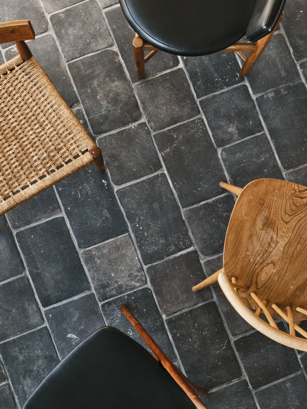 Chateau Villandry tiles by Claybrook Studio form a stone effect floor beneath wooden chairs