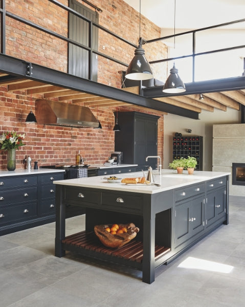 Industrial style shaker kitchen against exposed brick wall with steel beams overhead and indutrial lighting. Kitchen by Tom Howley.