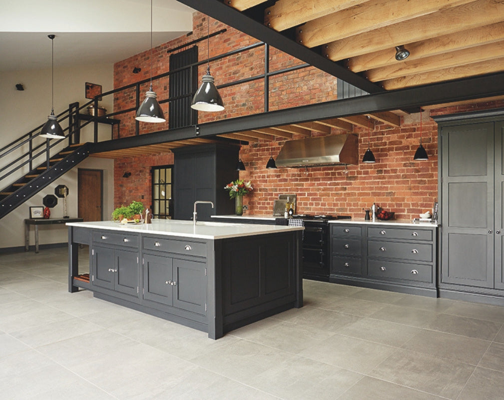 An industrial style shaker kitchen in charcoal grey complements the steel structure in the room and contasts with the exposed brick wall. Kitchen by Tom Howley.