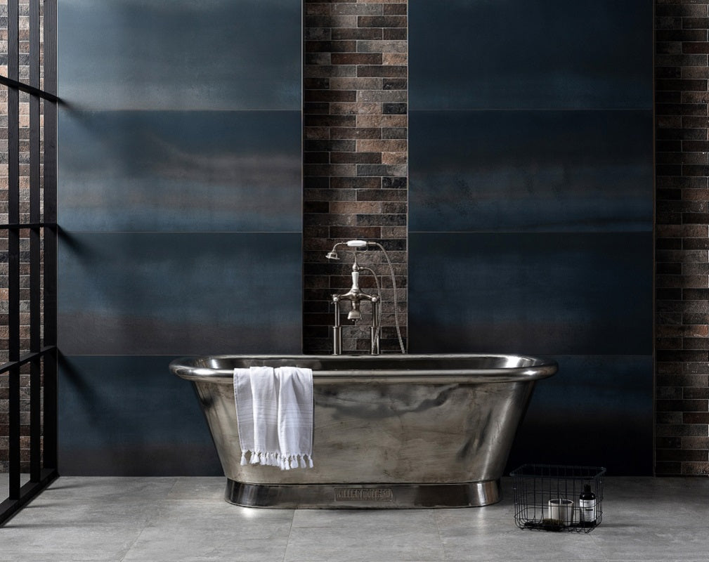 Industrial style bathroom featuring a freestanding nickel bathtub and extra large format blue metal effect porcelain wall tiles