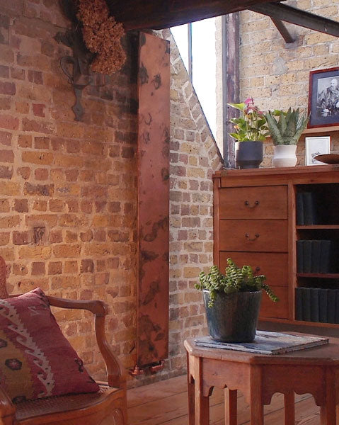 The Arteplano acid etched copper radiator from Bisque Radiators on an exposed brick wall in a converted warehouse home