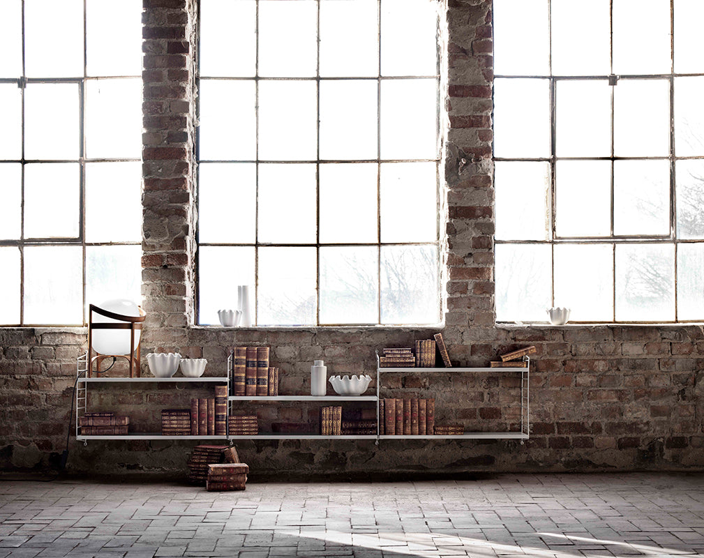 wall mounted shelving in a warehouse conversion with exposed brick wall and warehouse windows.