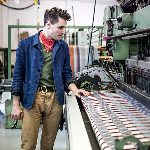 daniel harris of the london cloth company standing over a salvaged victorian loom.