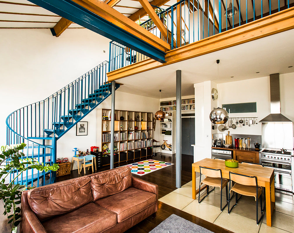 living room scheme of photographer debbie bragg showing a steel spiral staircase and vintage brown leather sofa