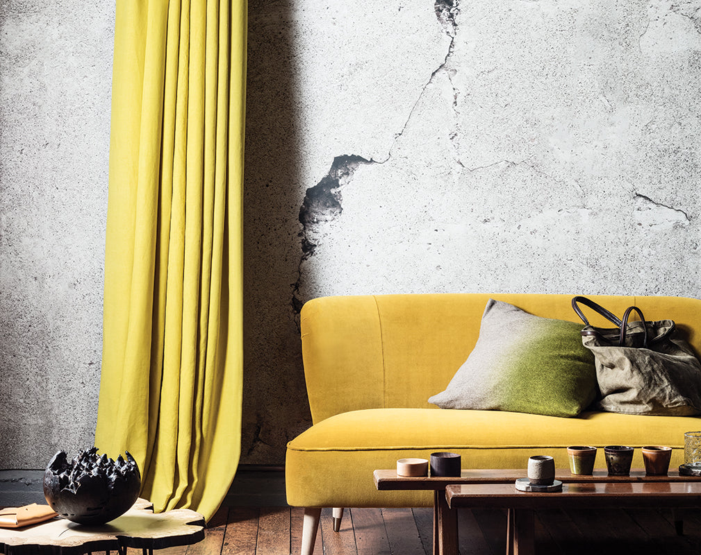 interior living room scheme with cracked concrete wall mural and ochre yellow accents