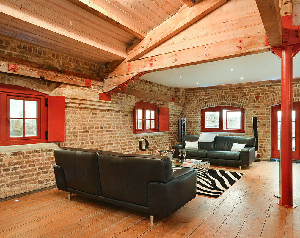 dramatic interior living space of london warehouse conversion at globe wharf with original timber beams and iron columns