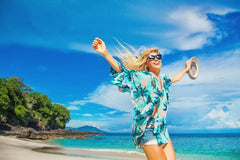 woman jumping on beach holding hat