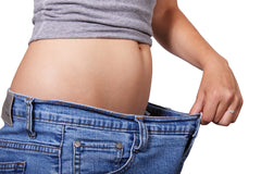 woman pulling at pants waist to show weight loss