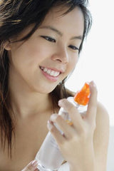 Asian woman looking at tea toner in spritz bottle