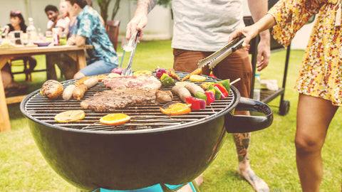 Closeup of man and woman grilling steaks