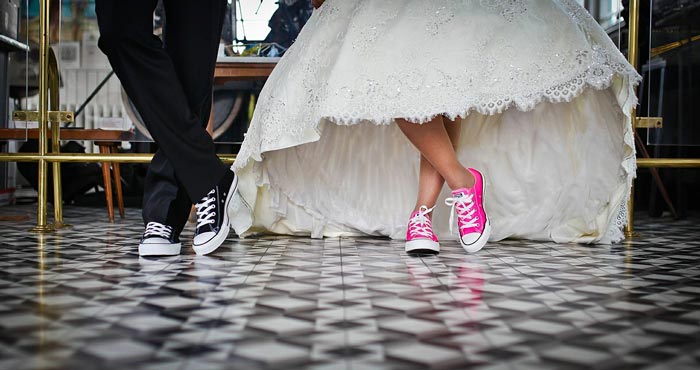 A couple in wedding attire wear lace sneakers.
