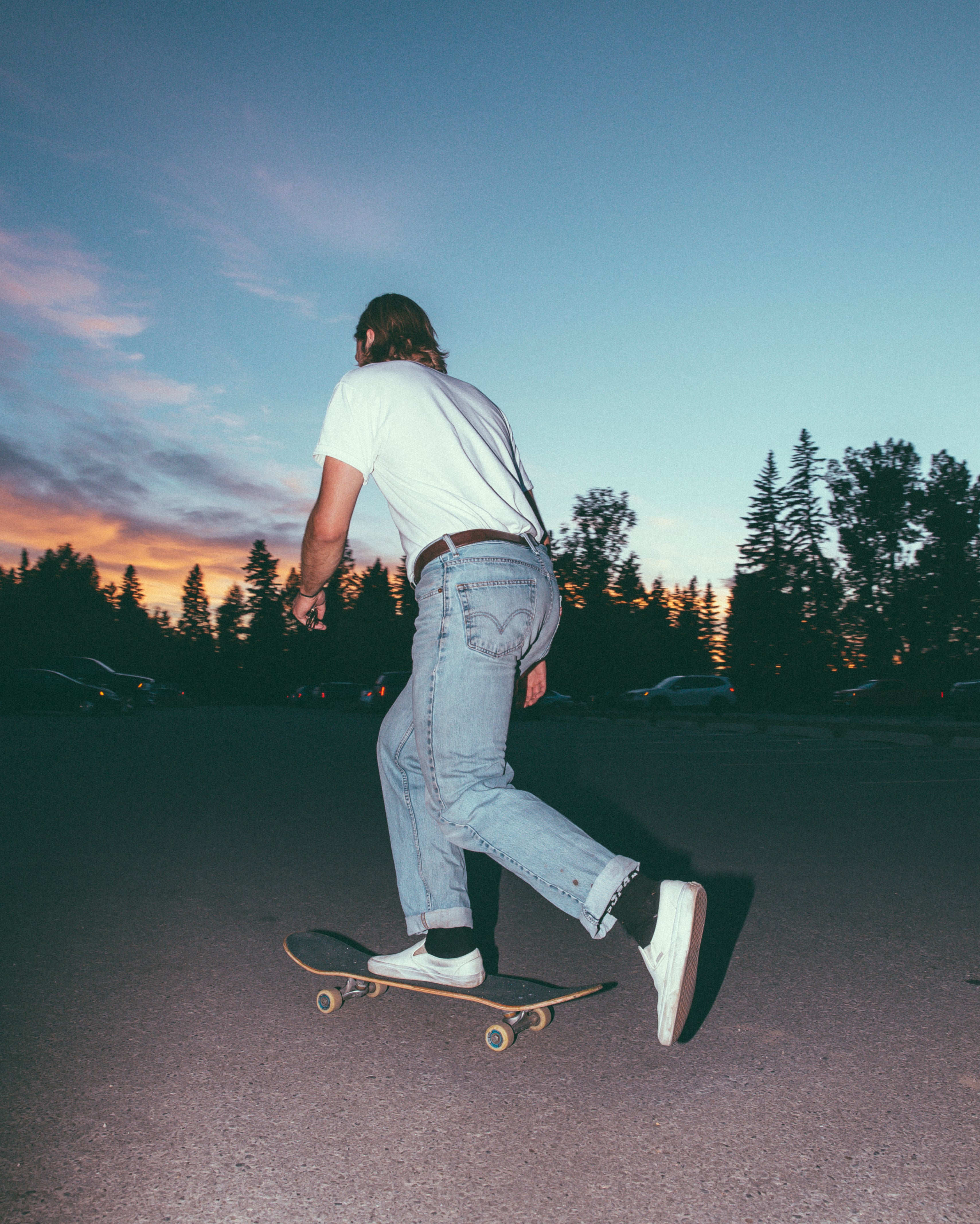 man pushing on skateboard at sunset