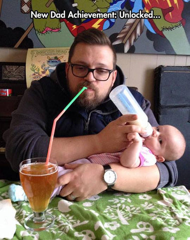 Dad drinking beer while feeding baby