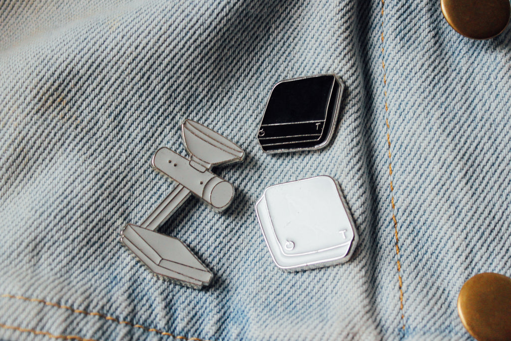 a trio of Acaia pins showcasing two scales and an Orion Bean Doser on a jacket