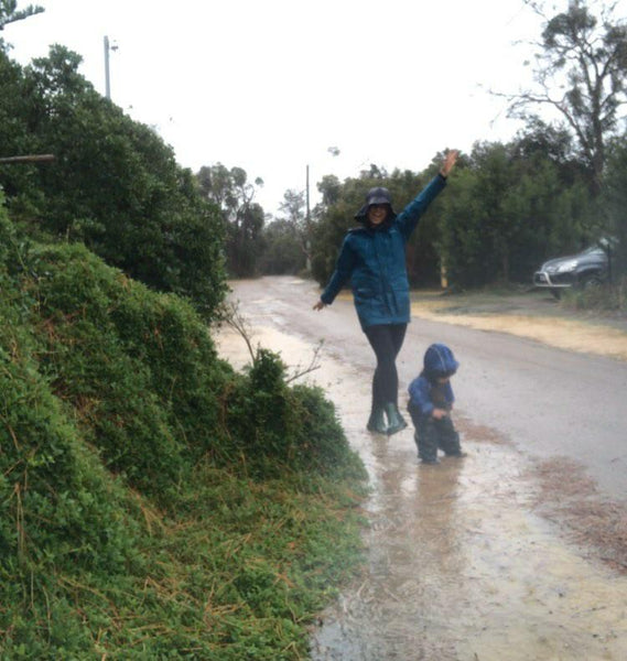 mum and sun walking through puddles in the rain