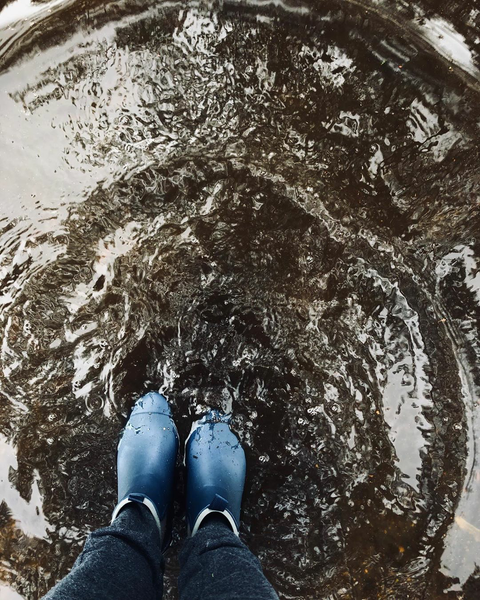 women wearing merry people blue boots, splashing in a puddle