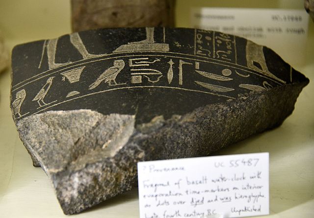 Fragment of a basalt water-clock, with evaporation time markers on interior as dots on djed and was hieroglyphs