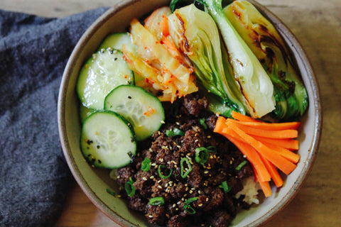 Ground Beef Bulgogi served over rice with bok choy, cucumbers, carrots, and kimchi