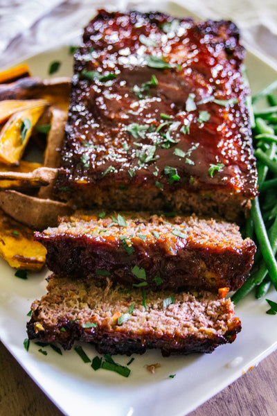 Sliced meatloaf with sweet potatoes and green beans.