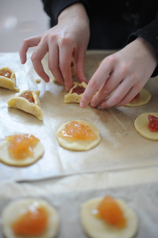 forming the triangle shape of the Hamantaschen