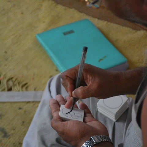 A blue pottery being painted on by an artisan