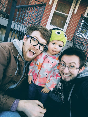 Two men and their daughter smiling.